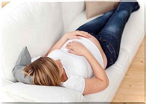 Pregnant woman lying on white sofa