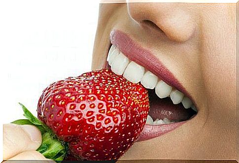 Healthy teeth biting a strawberry